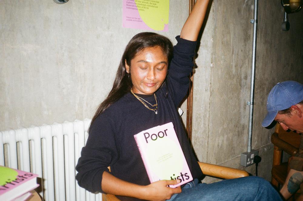 zarina posing with the book, eyes closed, arm in the air