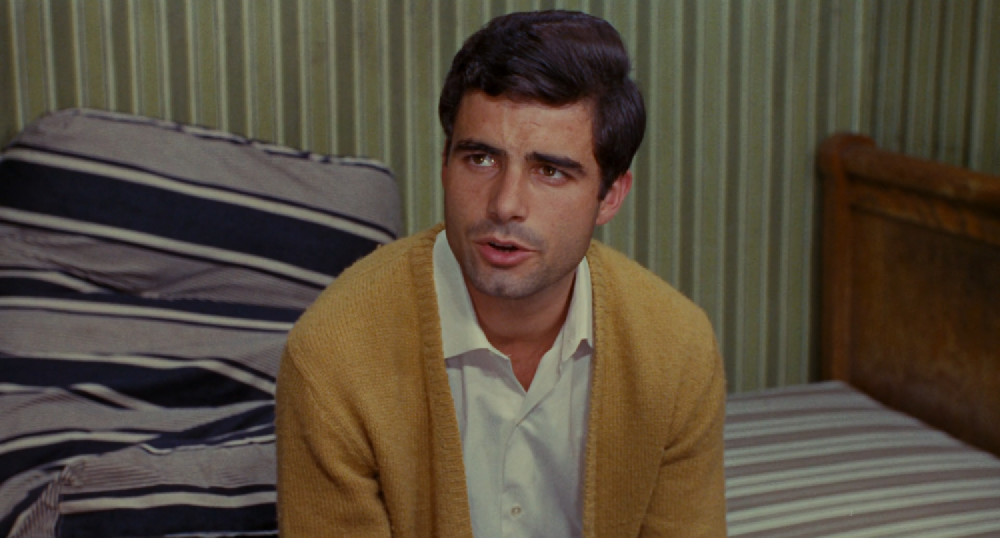 nino sat on the bed wearing a yellow cardigan