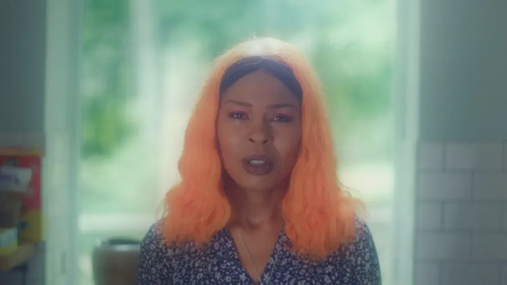 picture of Diamond Stingily with bright orange hair, crying, in a glowy room