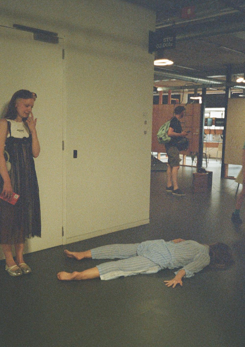 martina daniel telgmaa looking at an artwork of a body on the ground in pyjamas