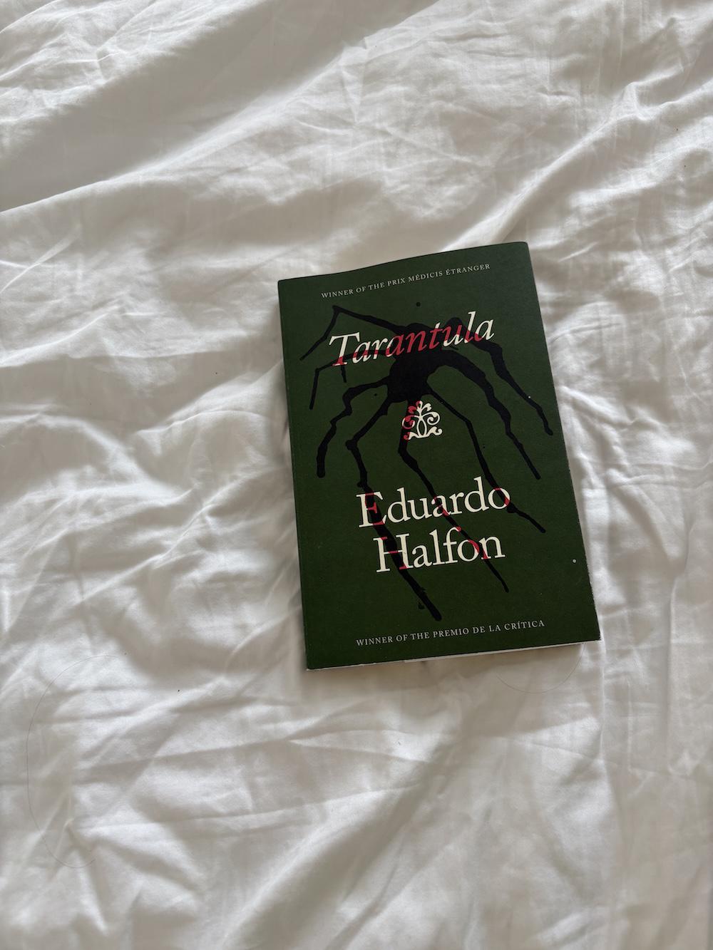 tarantula book on the bed, dark green cover with a spider design across the words