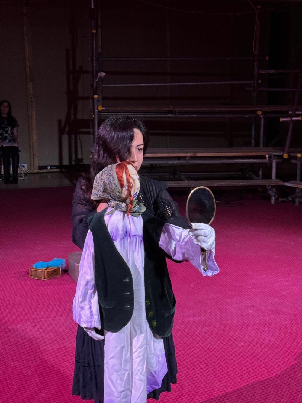 mahtab performing on stage with a puppet who is holding out a mirror to look at herself, or so they can look at themselves, because mahtab is right there too