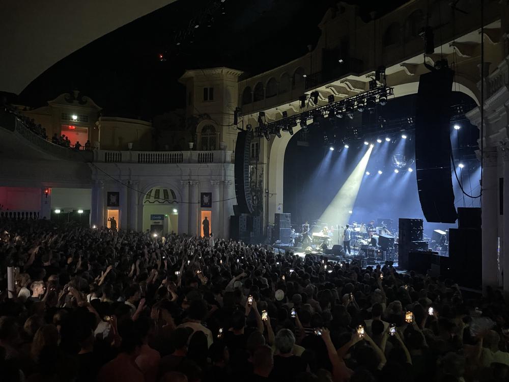 Nancy Whang spotlighted on stage at lcd soundsystem at a keyboard