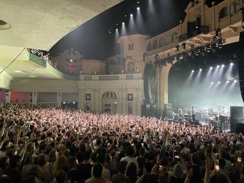 lights shining at the back of the band and across the room of people with their hands in their air for the final song at brixton academy