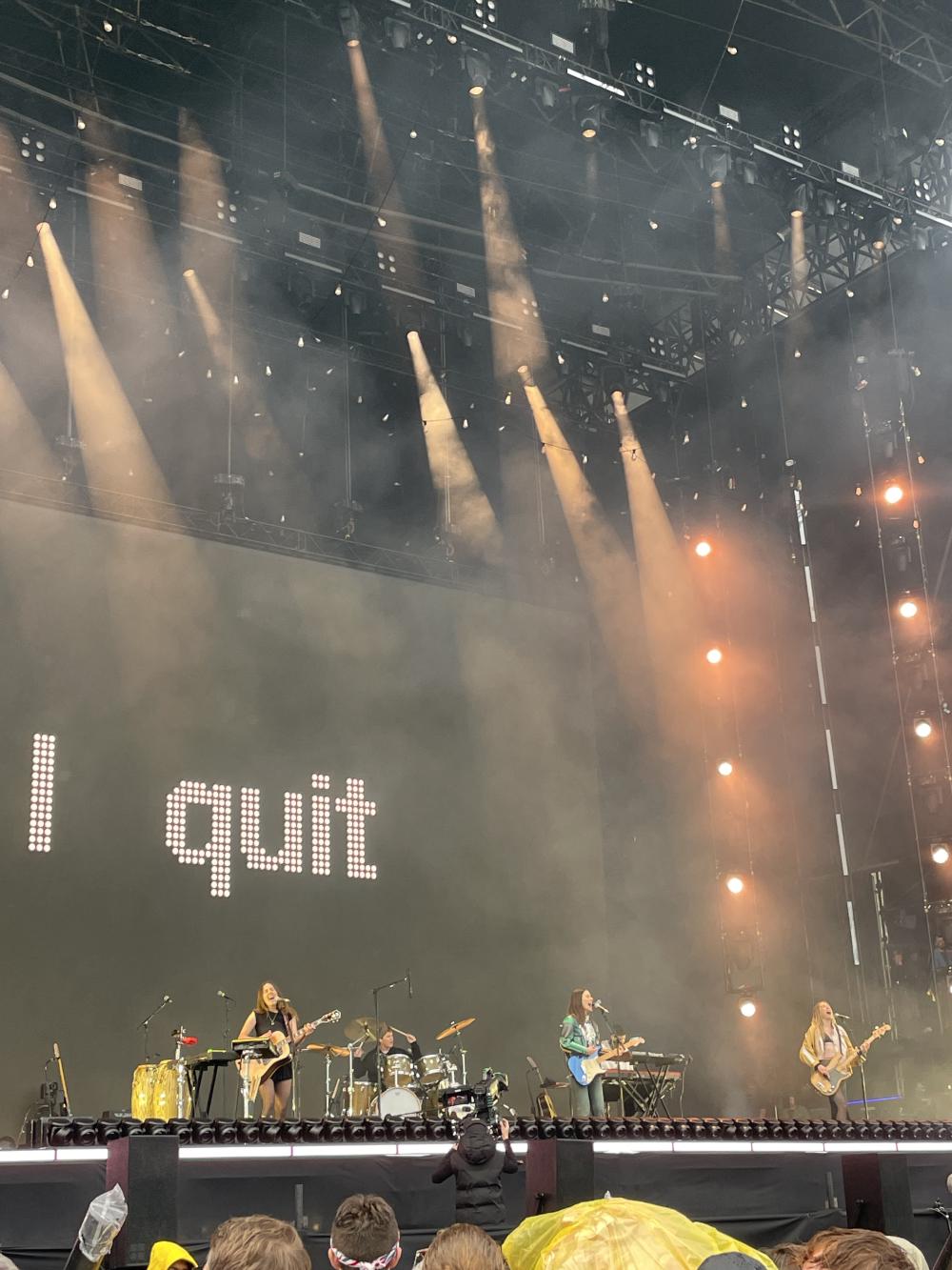 HAIM all holding guitars with a graphic behind them that says i quit
