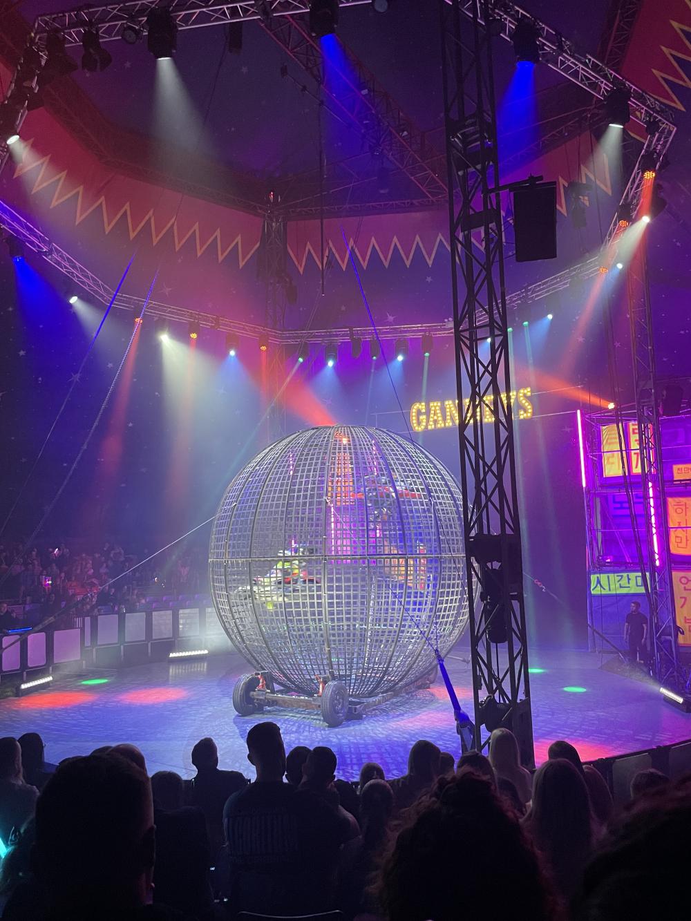 the globe of death is on the circus ring now with two motorbikes just visible inside beyond the metal grid the globe is made of