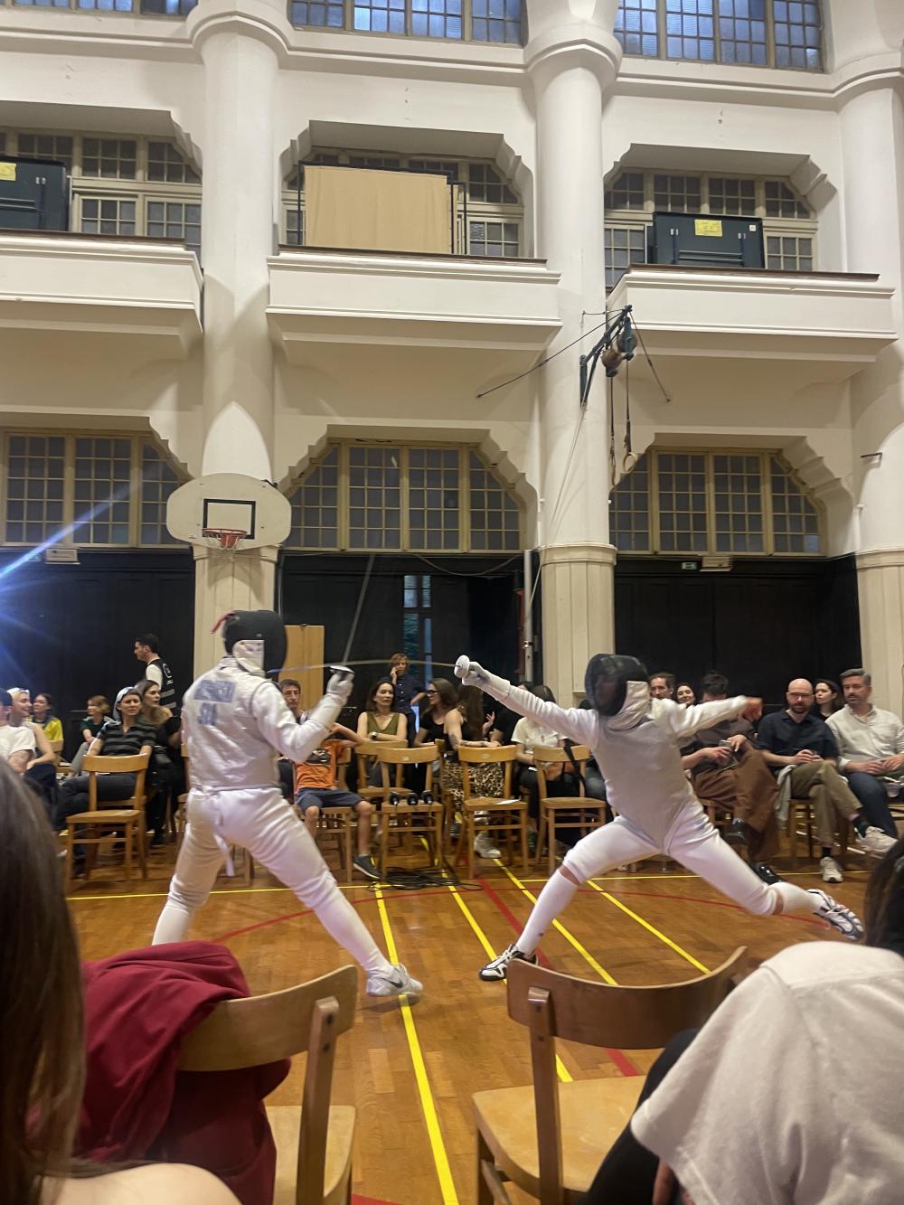 two people fencing in a sports hall