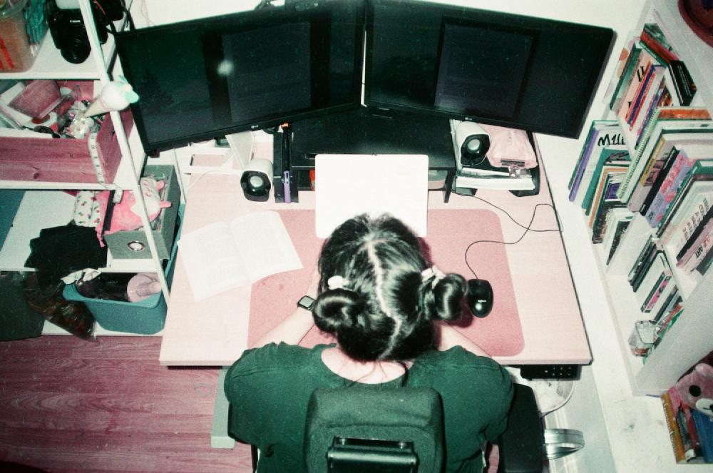 a photo taken overhead of gab in front of two computer screens with space buns in her hair