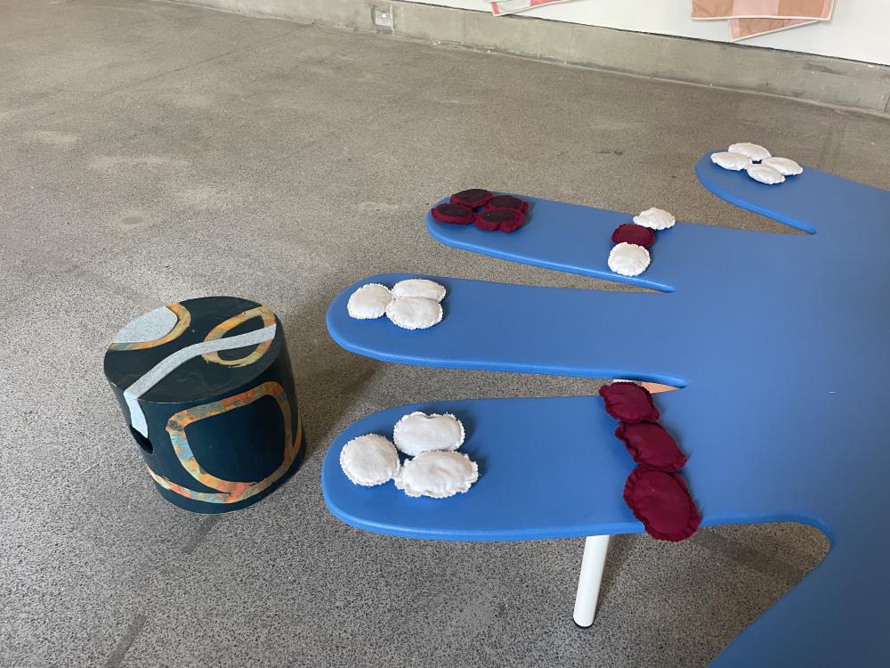 a view onto the other table showing some red and white circles of fabric stitched together