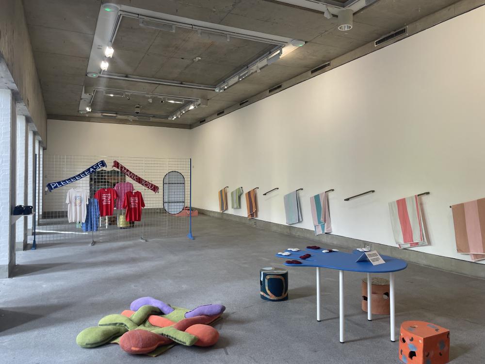 the main gallery in bluecoat with some towels on the wall, a table in the shape of a hand, a rack for hanging clothes, and some knitted long shapes on the bottom right that have been woven into what looks like a dog bed