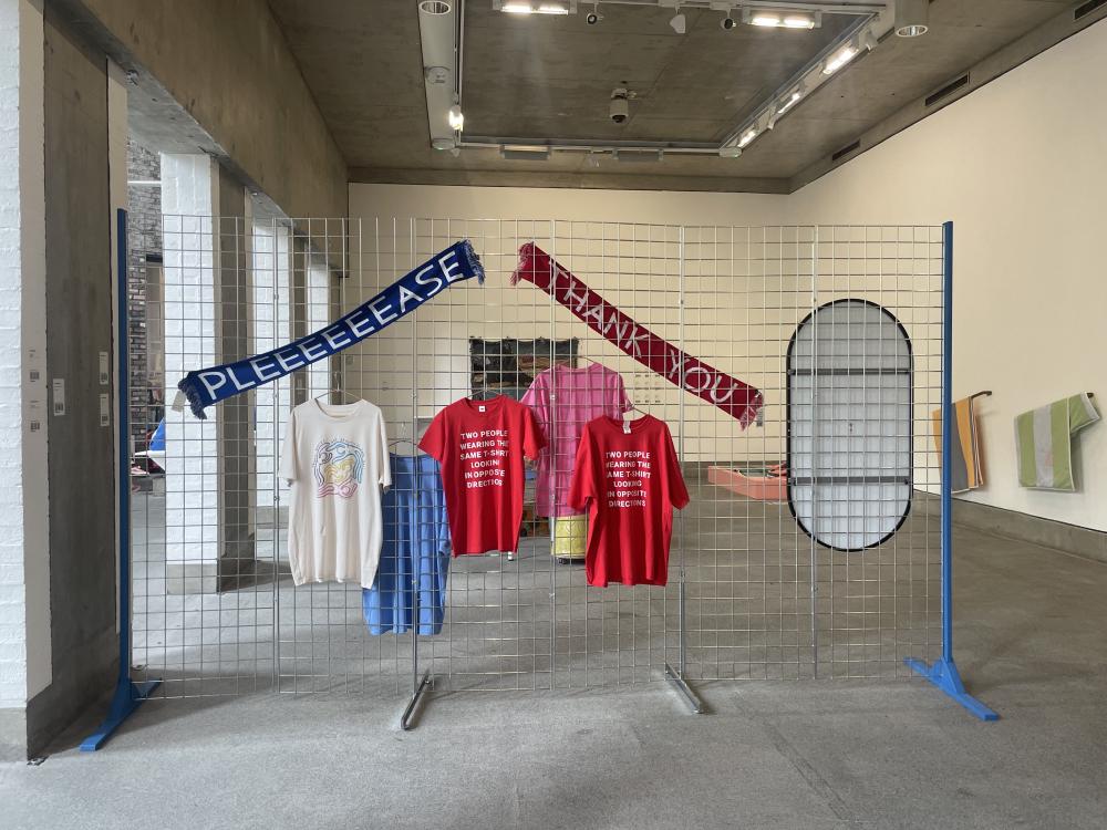 a closer view of the tshirts and the david shrigley scarves that says please and thank you alongside a mirror