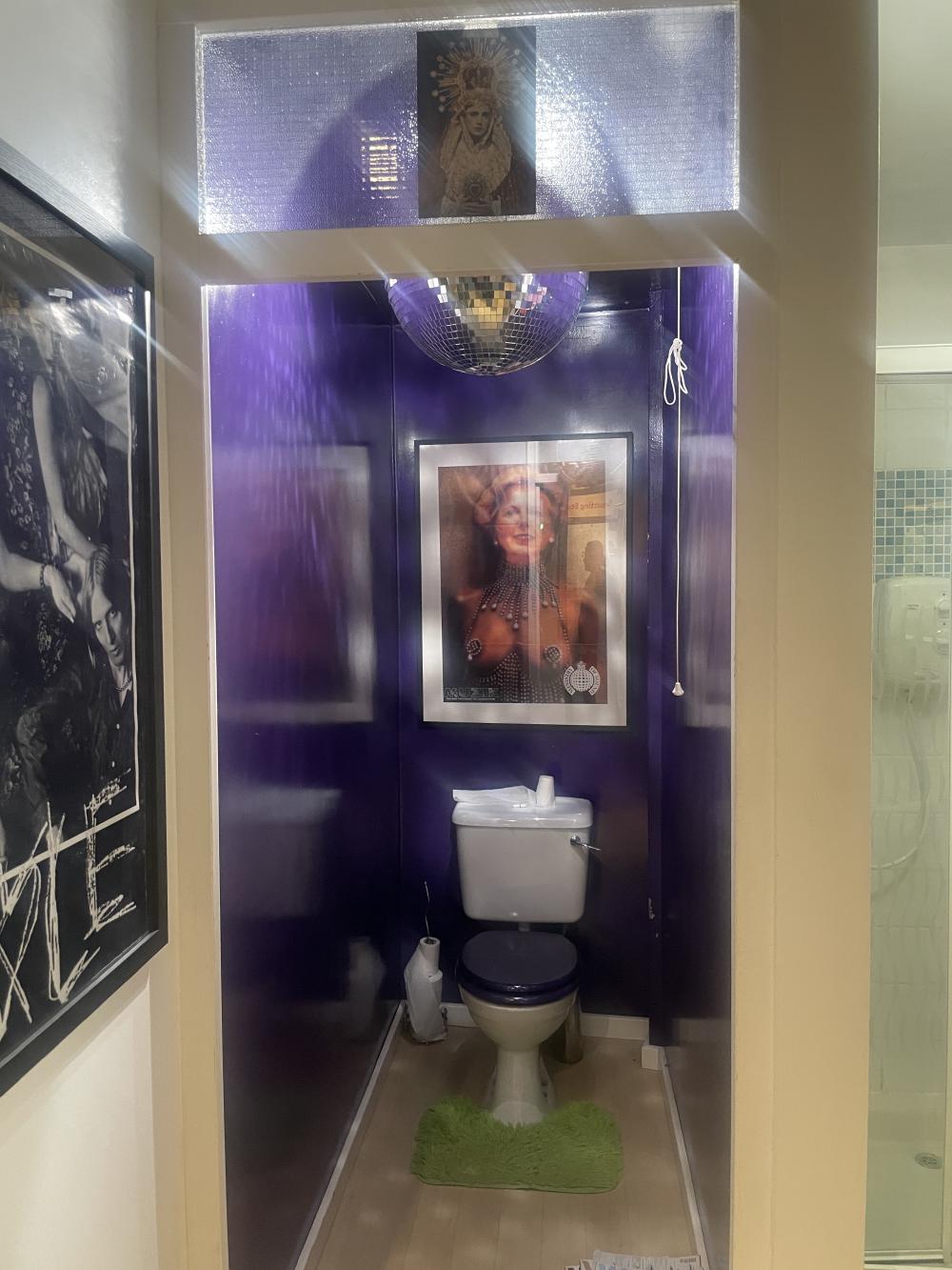 a toilet has been recreated from a flat in 2005 and the walls have been painted purple, theres a disco ball, and a framed picture of margaret thatcher with a kinky outfit on