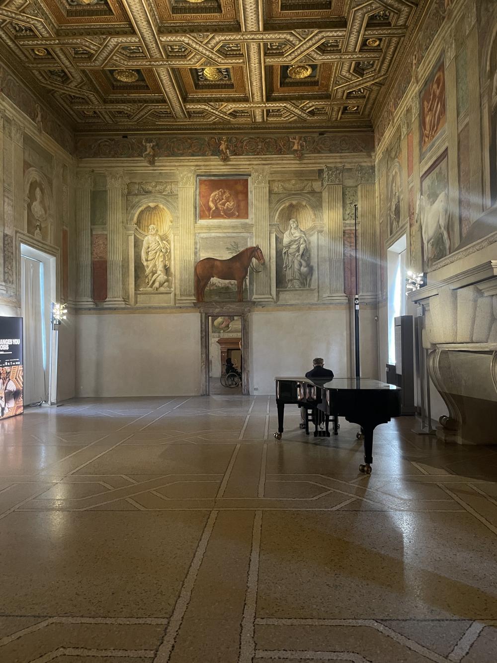 a view down one end of the room of horses in palazzo te showing a brown horse above the doorway at the far end