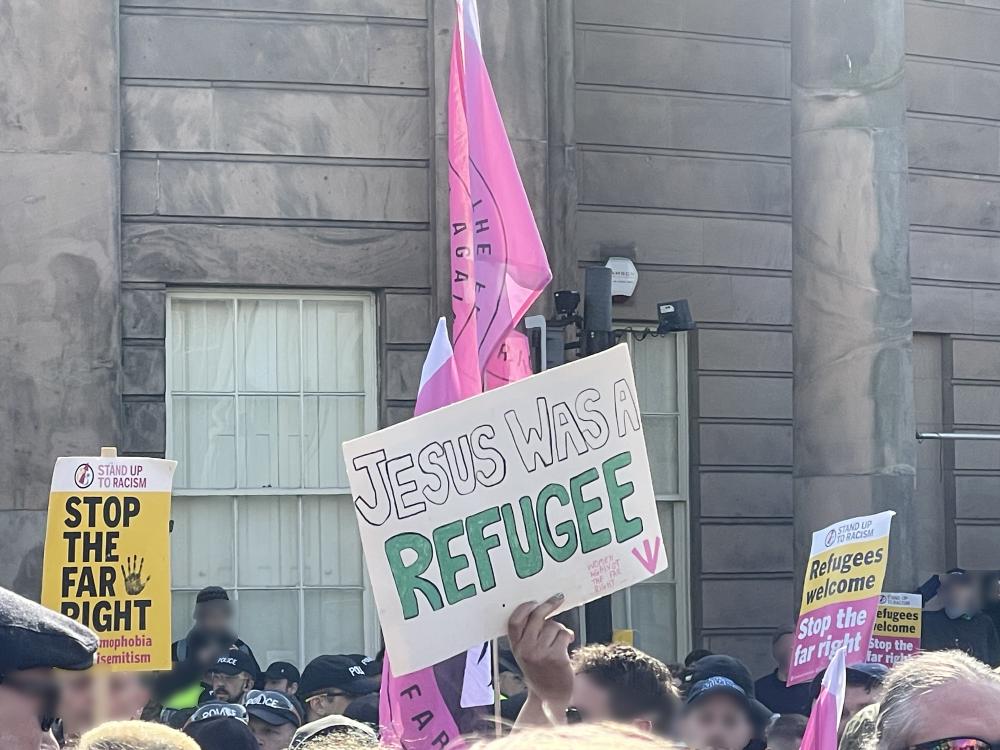 a counterprotester against ukip holds up a sign saying jesus was a refugee