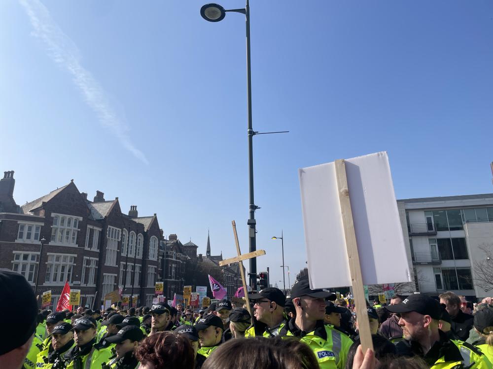 a wooden cross sticks out above the heads of police at a ukip protest in liverpool